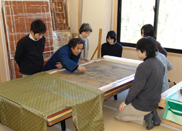Mr. Sekichi and the stafff of Sekichi Bokusendo Conservation Studio, Kyoto, examine a Chinese painting before treatment.
